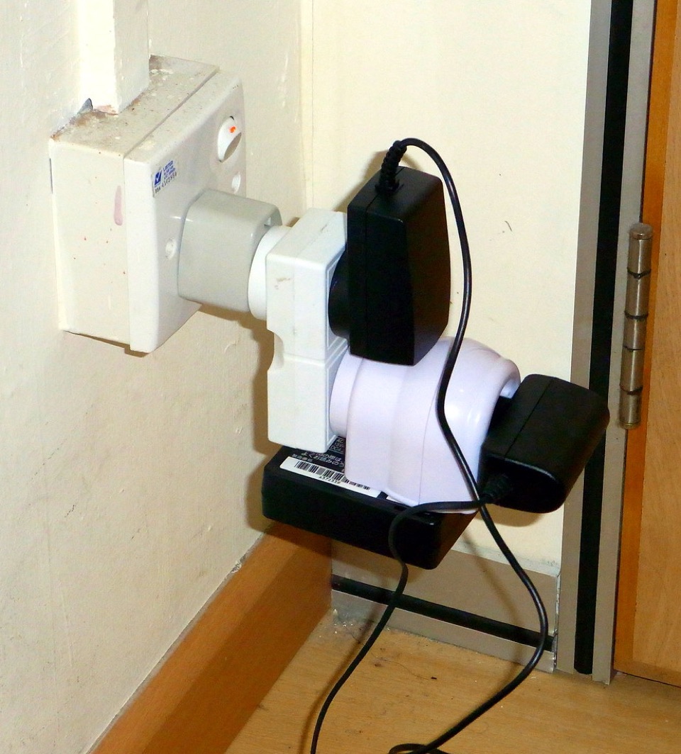 Several adaptors and plug-in power supplies stacked into one British wall socket