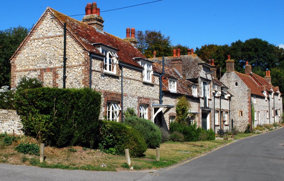 A row of flint fronted cottages under a clear sky at East Dean in East Sussex